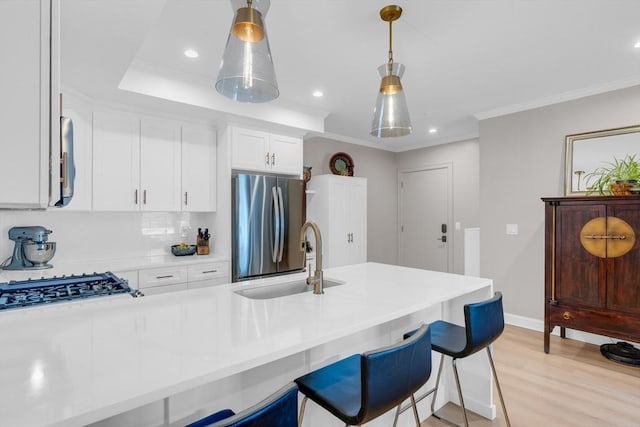 kitchen featuring freestanding refrigerator, a sink, white cabinetry, crown molding, and light wood-type flooring