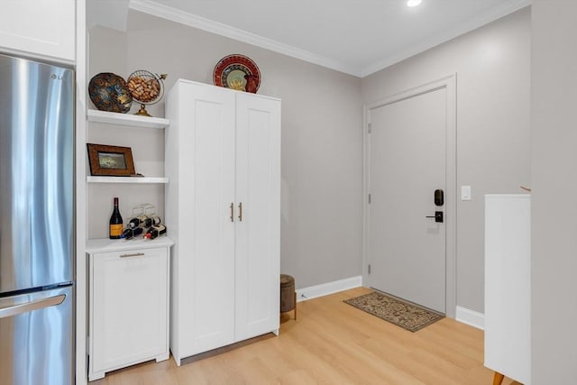 foyer entrance featuring baseboards, light wood-type flooring, and ornamental molding