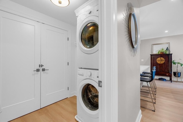 laundry area with recessed lighting, laundry area, light wood-style flooring, and stacked washer / drying machine