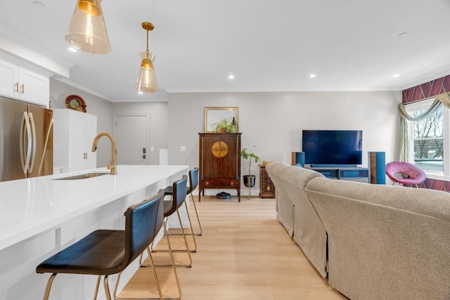 living area with light wood finished floors, recessed lighting, and ornamental molding