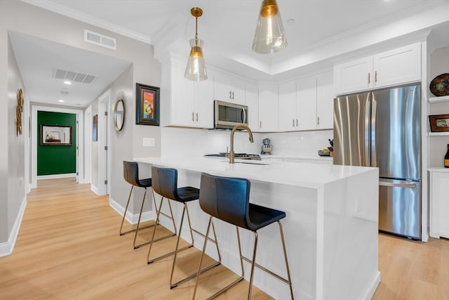 kitchen featuring visible vents, appliances with stainless steel finishes, light wood-type flooring, and a kitchen breakfast bar