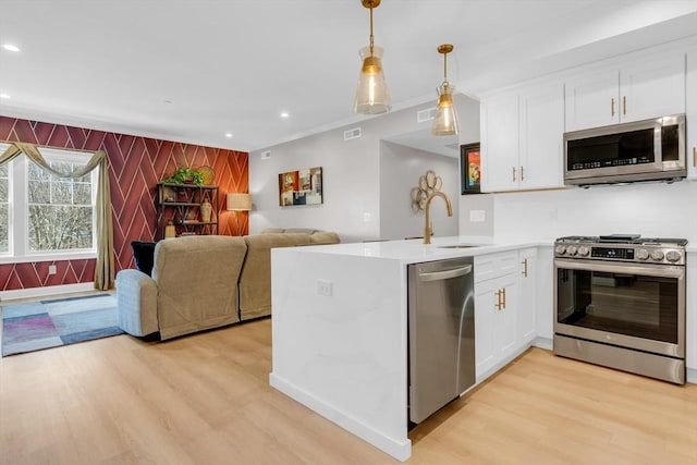 kitchen featuring a sink, light wood-style floors, appliances with stainless steel finishes, and white cabinetry