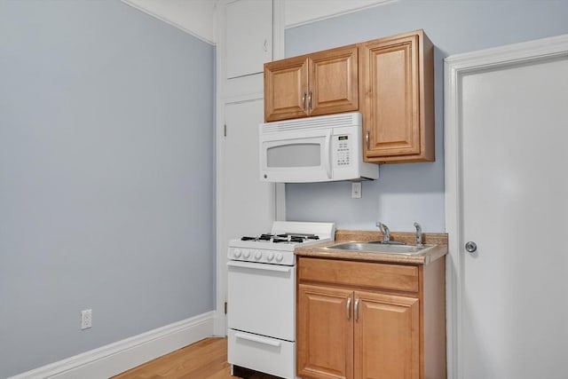 kitchen with sink, light hardwood / wood-style floors, and white appliances