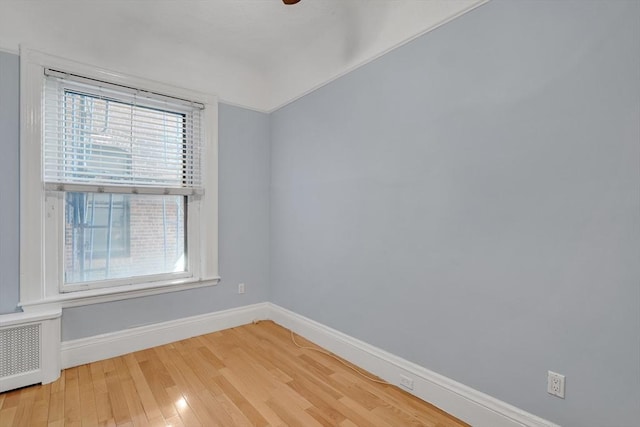 unfurnished room featuring hardwood / wood-style floors and radiator heating unit