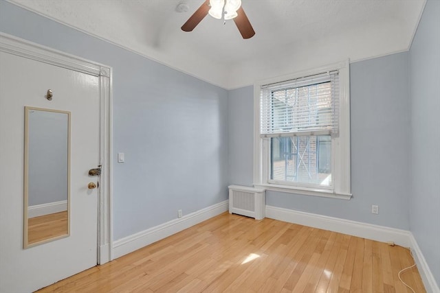 empty room featuring hardwood / wood-style floors, radiator, and ceiling fan