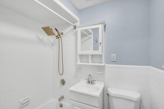 full bathroom with vanity, tiled shower / bath combo, toilet, and tile walls