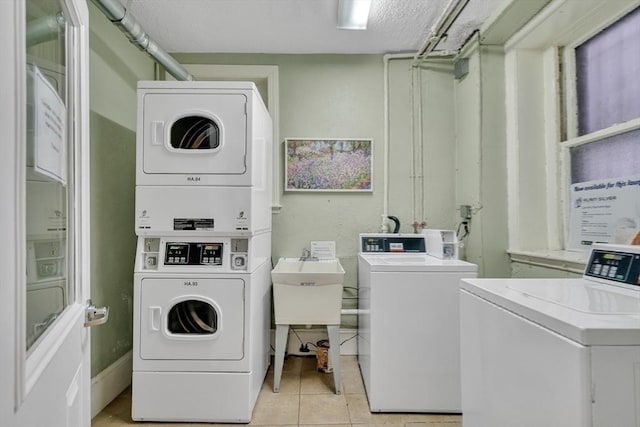 washroom with washing machine and clothes dryer, a textured ceiling, light tile patterned floors, and stacked washer / drying machine