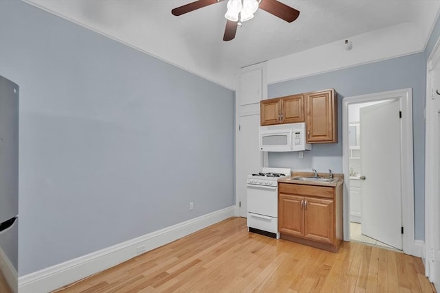 kitchen featuring white appliances, light hardwood / wood-style flooring, ceiling fan, and sink