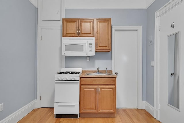 kitchen with white appliances, sink, and light hardwood / wood-style flooring