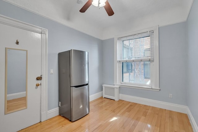 kitchen featuring ceiling fan, radiator, light wood-type flooring, and stainless steel refrigerator