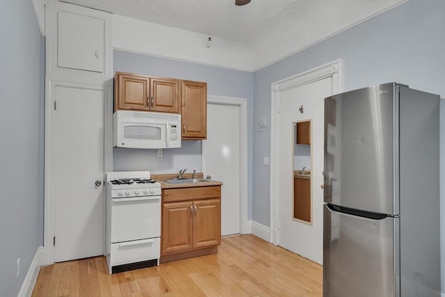 kitchen featuring white appliances, sink, and light hardwood / wood-style flooring