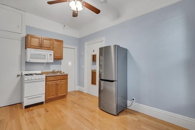 kitchen with ceiling fan, sink, light hardwood / wood-style floors, and white appliances