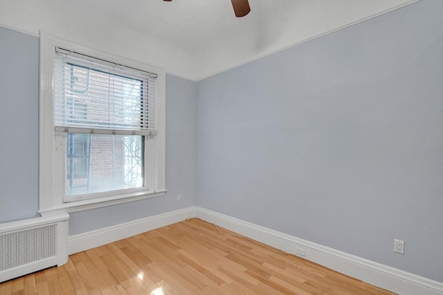 spare room featuring ceiling fan, radiator heating unit, and hardwood / wood-style floors