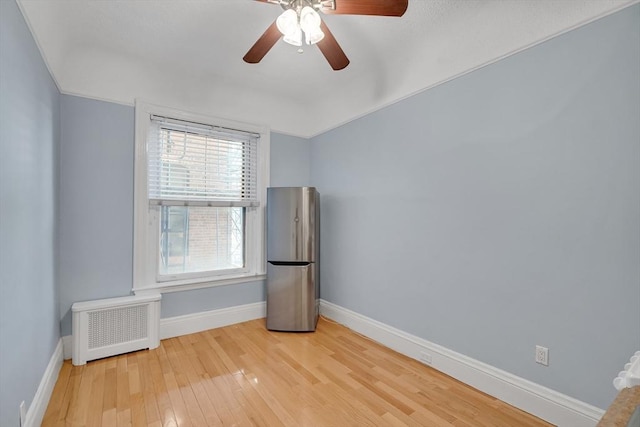 unfurnished room featuring hardwood / wood-style flooring, radiator, and ceiling fan