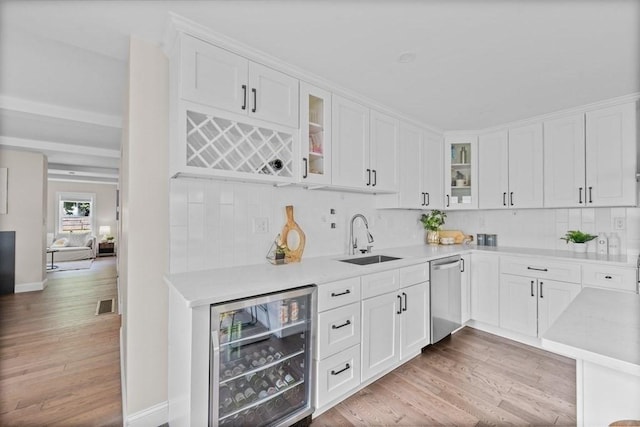 kitchen featuring white cabinets, sink, stainless steel dishwasher, decorative backsplash, and beverage cooler