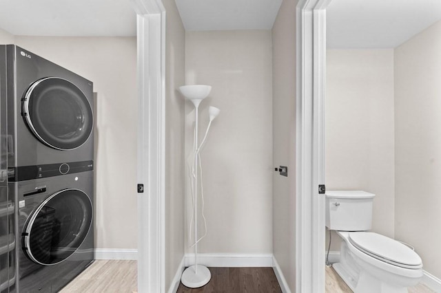 washroom with hardwood / wood-style floors and stacked washer / drying machine