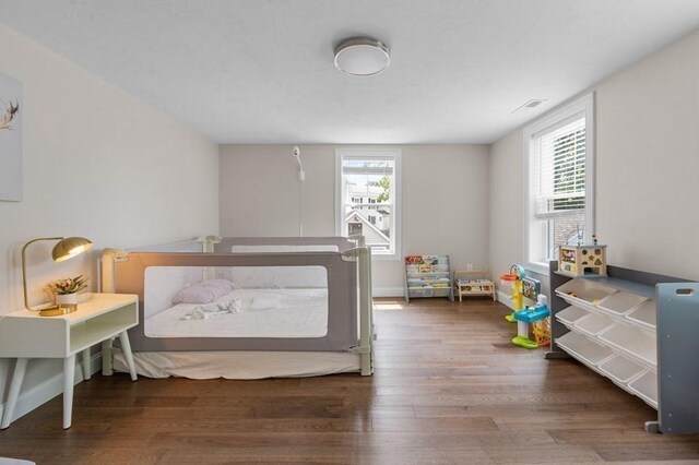 bedroom with dark hardwood / wood-style floors and multiple windows