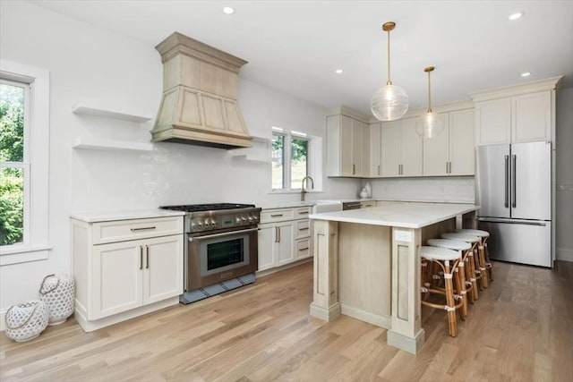 kitchen featuring a center island, stainless steel appliances, light countertops, backsplash, and light wood-style floors