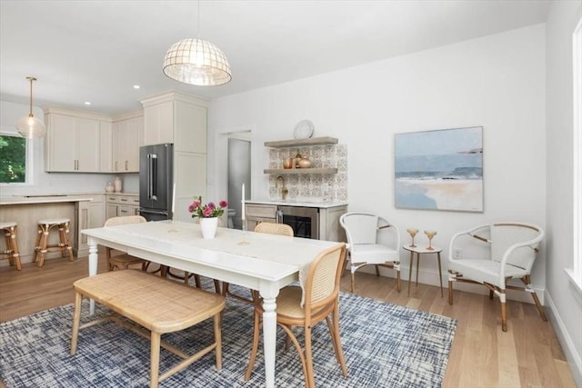 dining area featuring light wood-type flooring, beverage cooler, baseboards, and recessed lighting