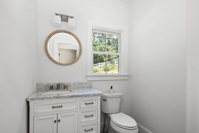 bathroom with toilet, vanity, and baseboards