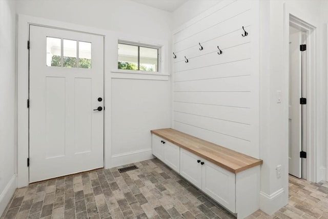 mudroom featuring brick floor, visible vents, and baseboards