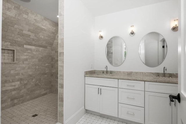 bathroom featuring double sink vanity, a tile shower, and tile patterned floors