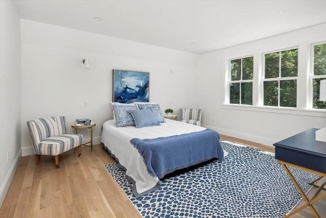 bedroom with multiple windows, baseboards, and wood finished floors