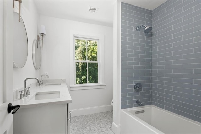 full bathroom with double vanity, toilet, and tiled shower / bath combo