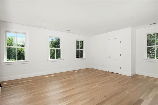 empty room with light wood-style flooring, visible vents, and baseboards