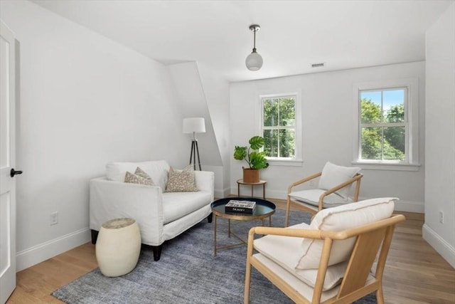 living area featuring visible vents, baseboards, and wood finished floors