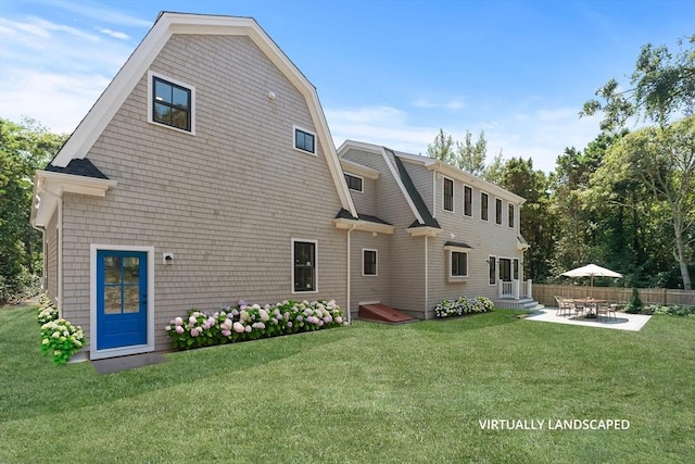 back of property with entry steps, a patio, a gambrel roof, fence, and a yard