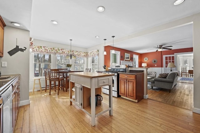 kitchen featuring hanging light fixtures, light hardwood / wood-style flooring, a breakfast bar, and appliances with stainless steel finishes