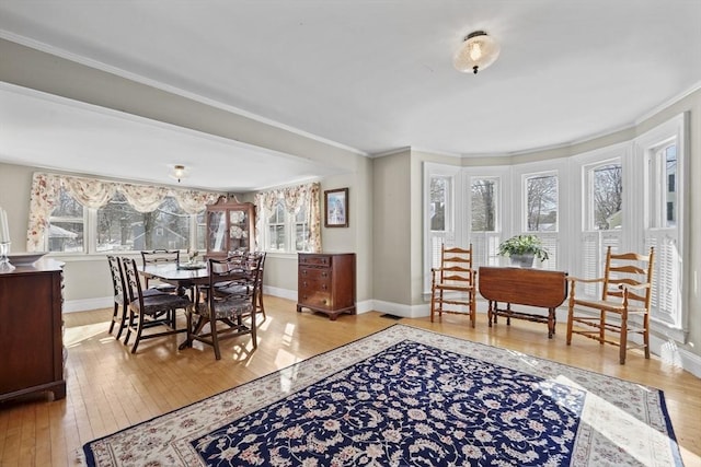 dining area featuring crown molding and light wood-type flooring