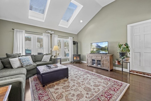 living room with high vaulted ceiling, a wood stove, dark hardwood / wood-style flooring, and a skylight