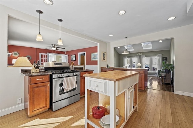 kitchen featuring light wood-type flooring, a center island, butcher block countertops, and stainless steel gas range oven