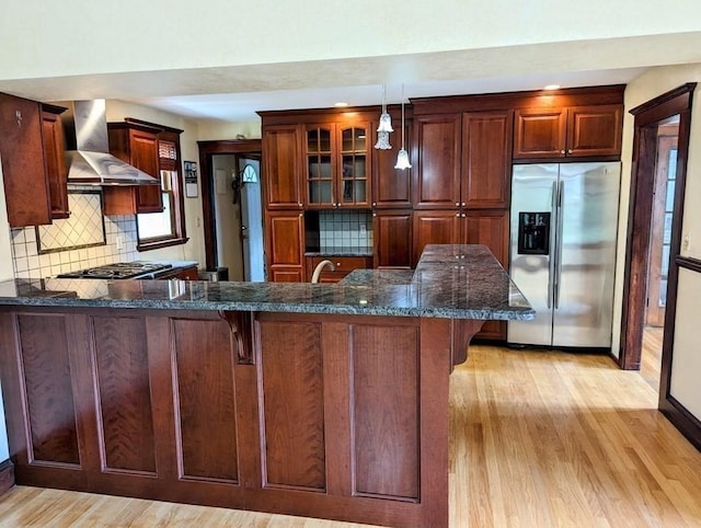 43 Brunswick Rd, Arlington, MA 02474 - kitchen with wall chimney range hood, decorative backsplash, stainless steel appliances, and light wood-style flooring