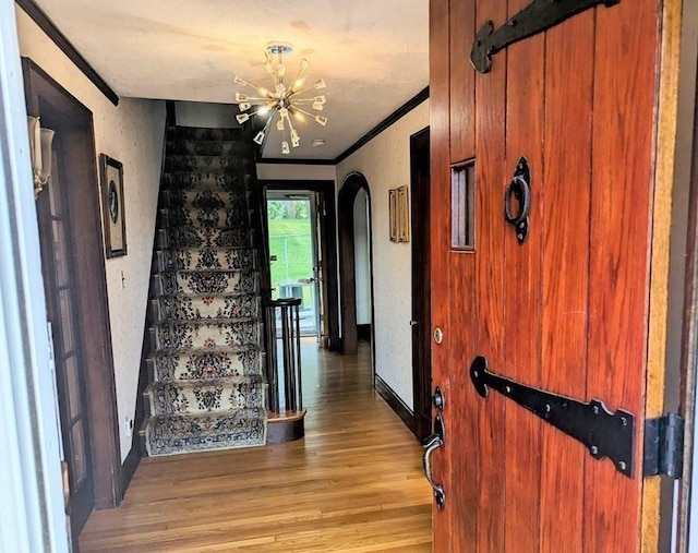 43 Brunswick Rd, Arlington, MA 02474 - entrance foyer with crown molding, stairs, arched walkways, light wood-style flooring, and a notable chandelier