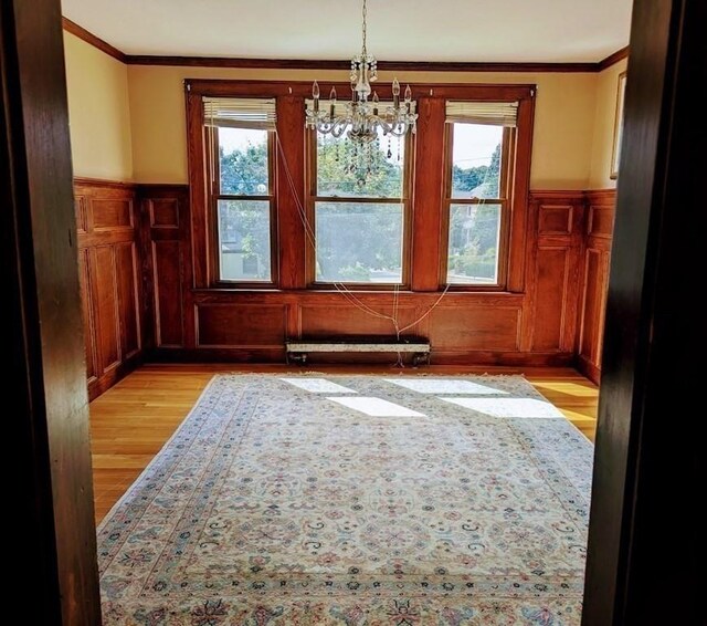 43 Brunswick Rd, Arlington, MA 02474 - unfurnished dining area featuring a notable chandelier, ornamental molding, light wood-style flooring, and a wainscoted wall