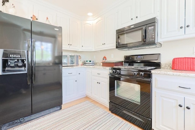 kitchen featuring black appliances, white cabinets, light wood-style flooring, and light stone counters