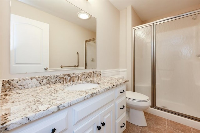 bathroom with a stall shower, toilet, vanity, and tile patterned floors
