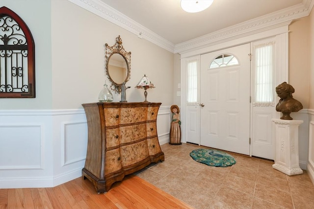 entryway featuring a decorative wall, wainscoting, and ornamental molding