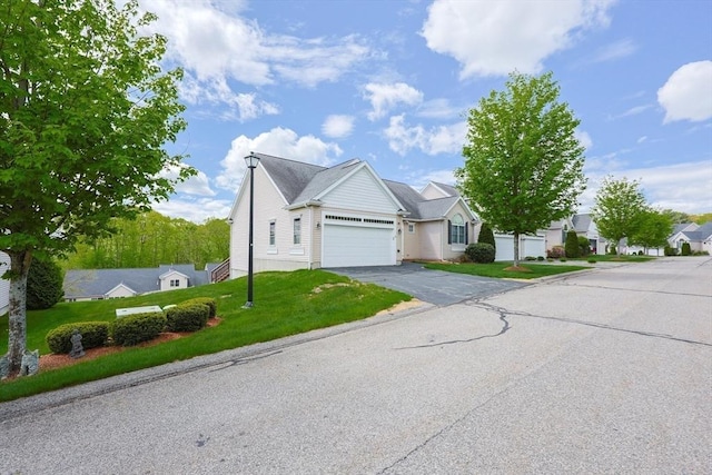 view of front of house with an attached garage, asphalt driveway, a front lawn, and a residential view