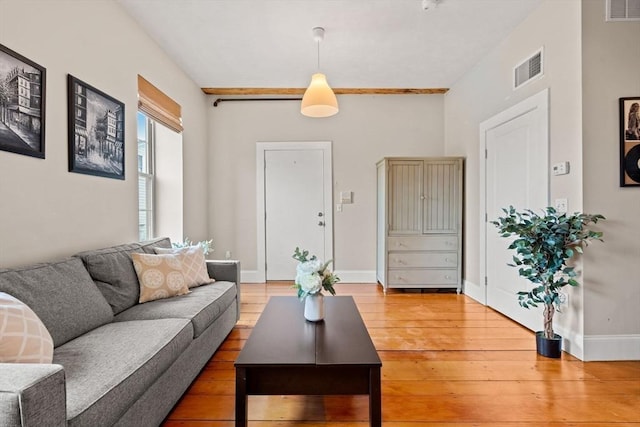 living area with wood finished floors, visible vents, and baseboards