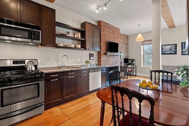 kitchen with light stone counters, light wood finished floors, open shelves, dark brown cabinets, and appliances with stainless steel finishes