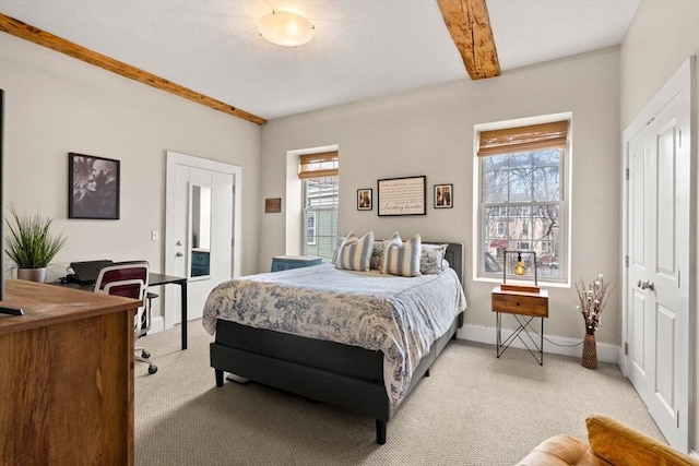 bedroom featuring beamed ceiling, multiple windows, light colored carpet, and baseboards