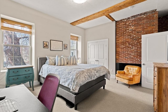 bedroom with beam ceiling, light colored carpet, baseboards, and a closet