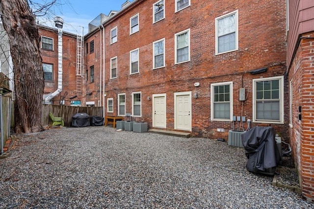 back of property featuring brick siding, central air condition unit, and fence