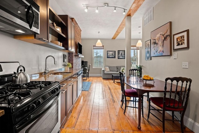 kitchen featuring dark stone countertops, visible vents, light wood-style flooring, a sink, and stainless steel appliances