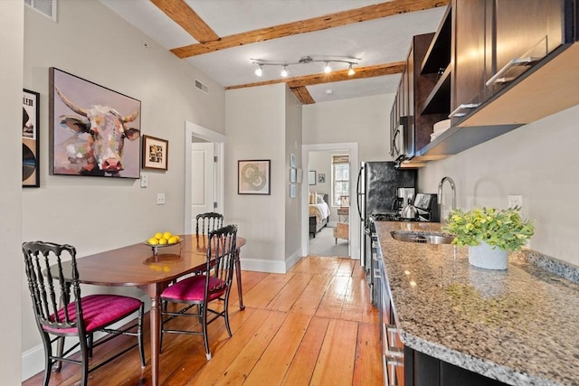 dining room with beam ceiling, baseboards, visible vents, and light wood finished floors