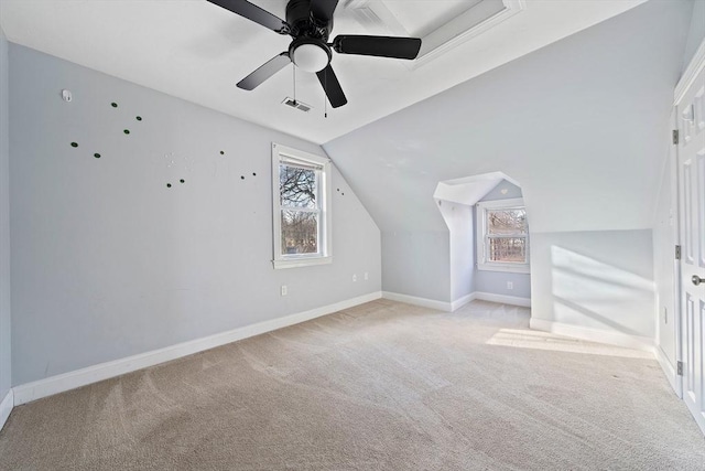 additional living space with ceiling fan, light colored carpet, a healthy amount of sunlight, and vaulted ceiling